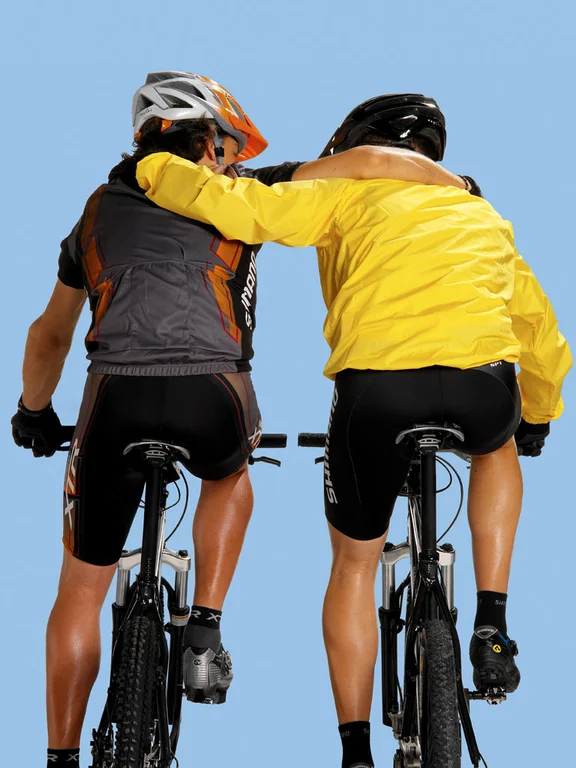 zwei männliche Personen umarmen sich beim Fahrradfahren, Blick von hinten unten