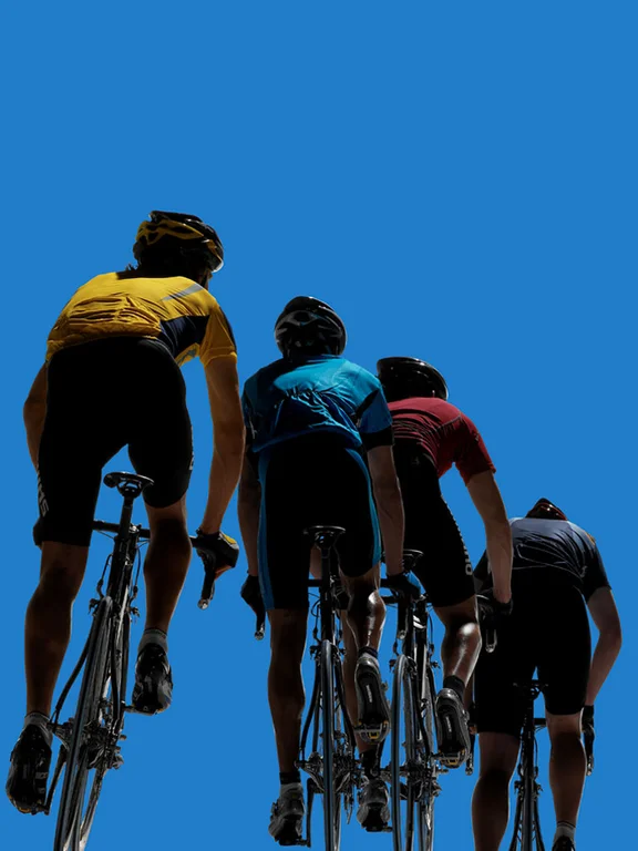 vier Personen auf Rennrädern die hintereinander fahren, Blick von schräg unten in den blauen Himmel