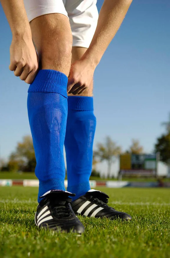 Person in Fußballschuhen zieht sich die Socken hoch