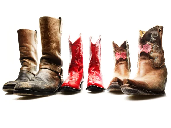 drei unterschiedliche Cowboystiefelpaar in braun und rot auf weißem Boden