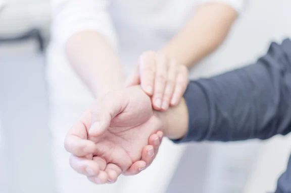 Ärztin misst Puls am Handgelenk eines Patienten