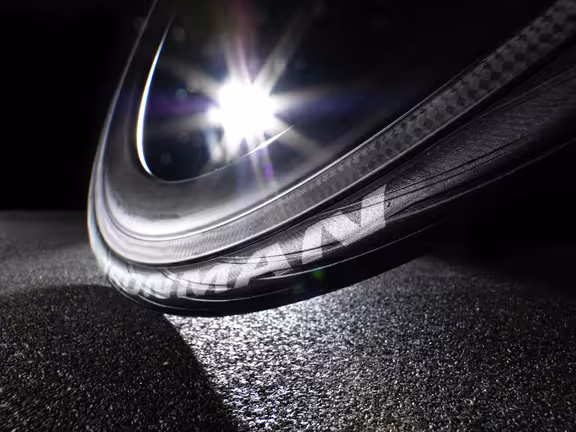 Nahaufnahme von einem Fahrradrad der von hinten angeleuchtet wird, Untergrund ist eine Straße