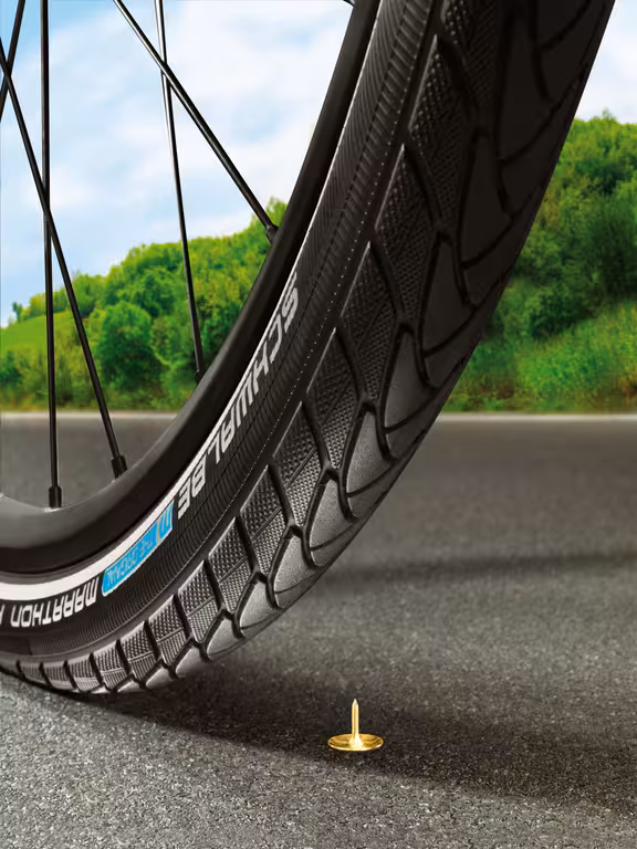 Fahrradrad der kurz davor ist über eine Heftzwecke auf einer Straße zu rollen