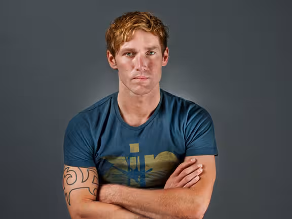 männliche Person mit roten kurzen Haaren in Tshirt und verschränkten Armen